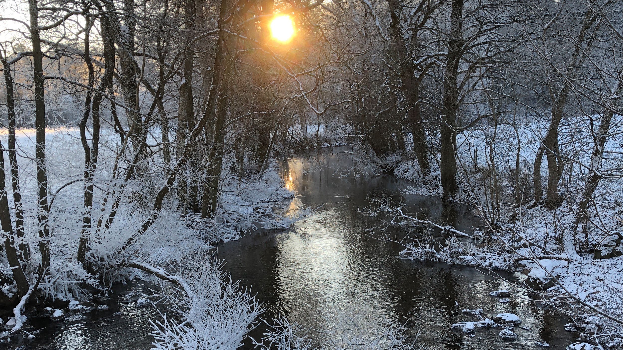 Snö och is i vintersol över å. Foto Håkan Persson